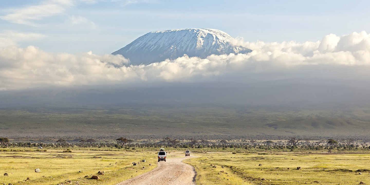 Safari vehicles on a track across the Tanzanian plains